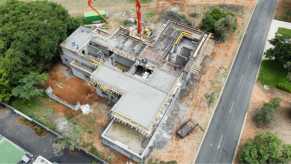 Overhead perspective of a house being built, highlighting the structural framework and construction activity.