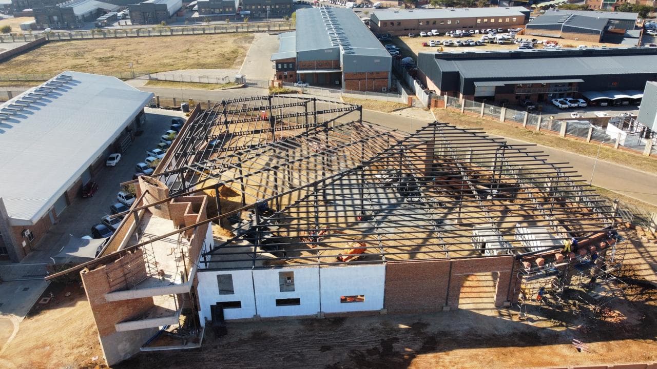 Aerial view of a construction site showcasing a building in progress, with cranes and scaffolding visible.